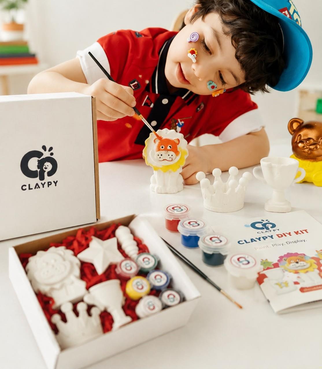 Child painting a Claypy lion figurine from a DIY painting kit